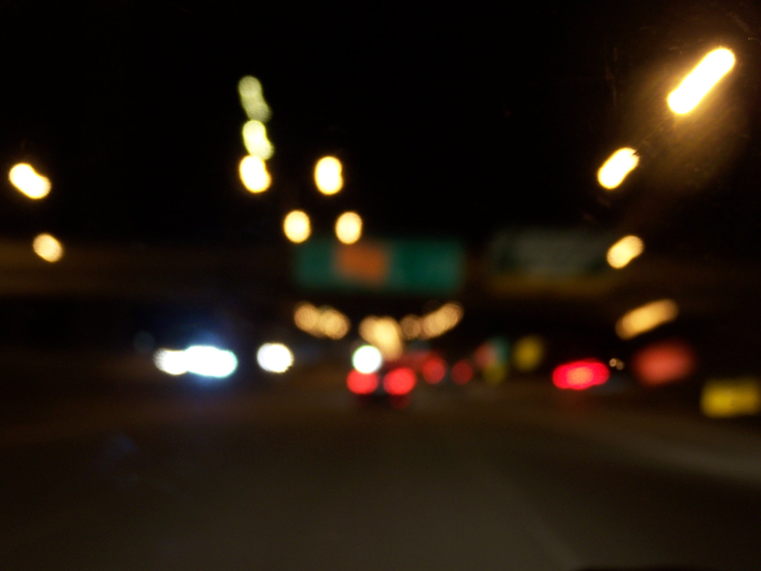 low lit freeway at night. the streetlamps and car lights are a blurred, and nearly the only visible element.