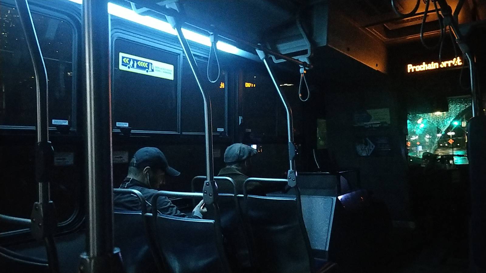 interior of a french bus at night time, with dim, deep blue interior lighting.