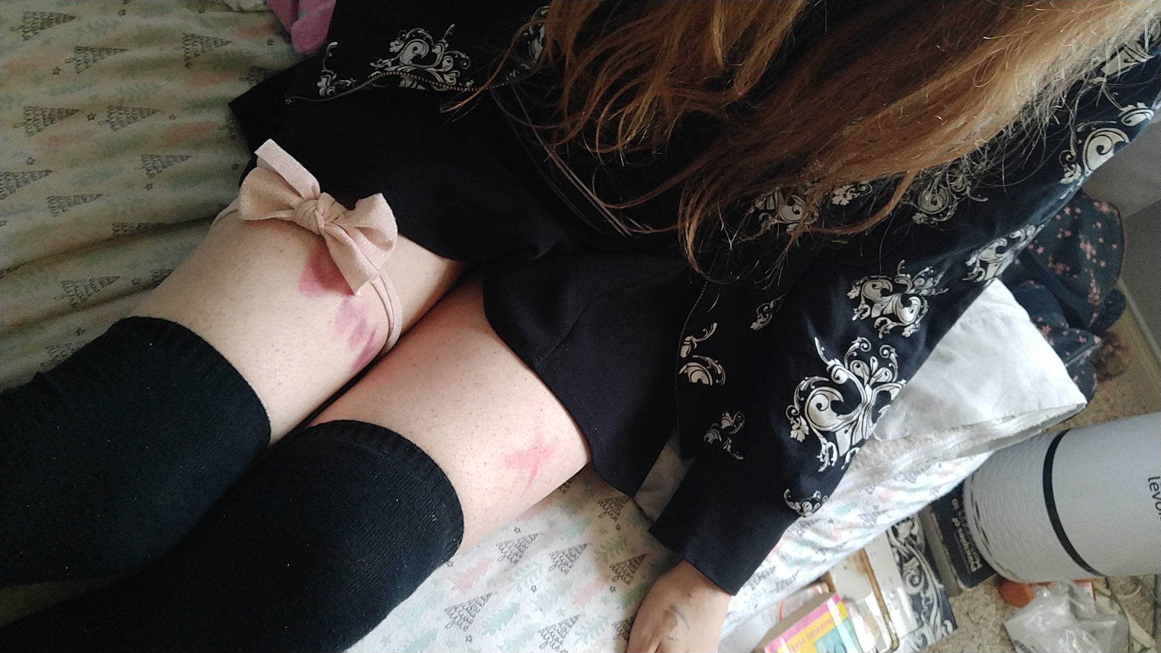ely in a black sweater and skirt with red makeup on its thighs and ribbon around it. black thigh highs