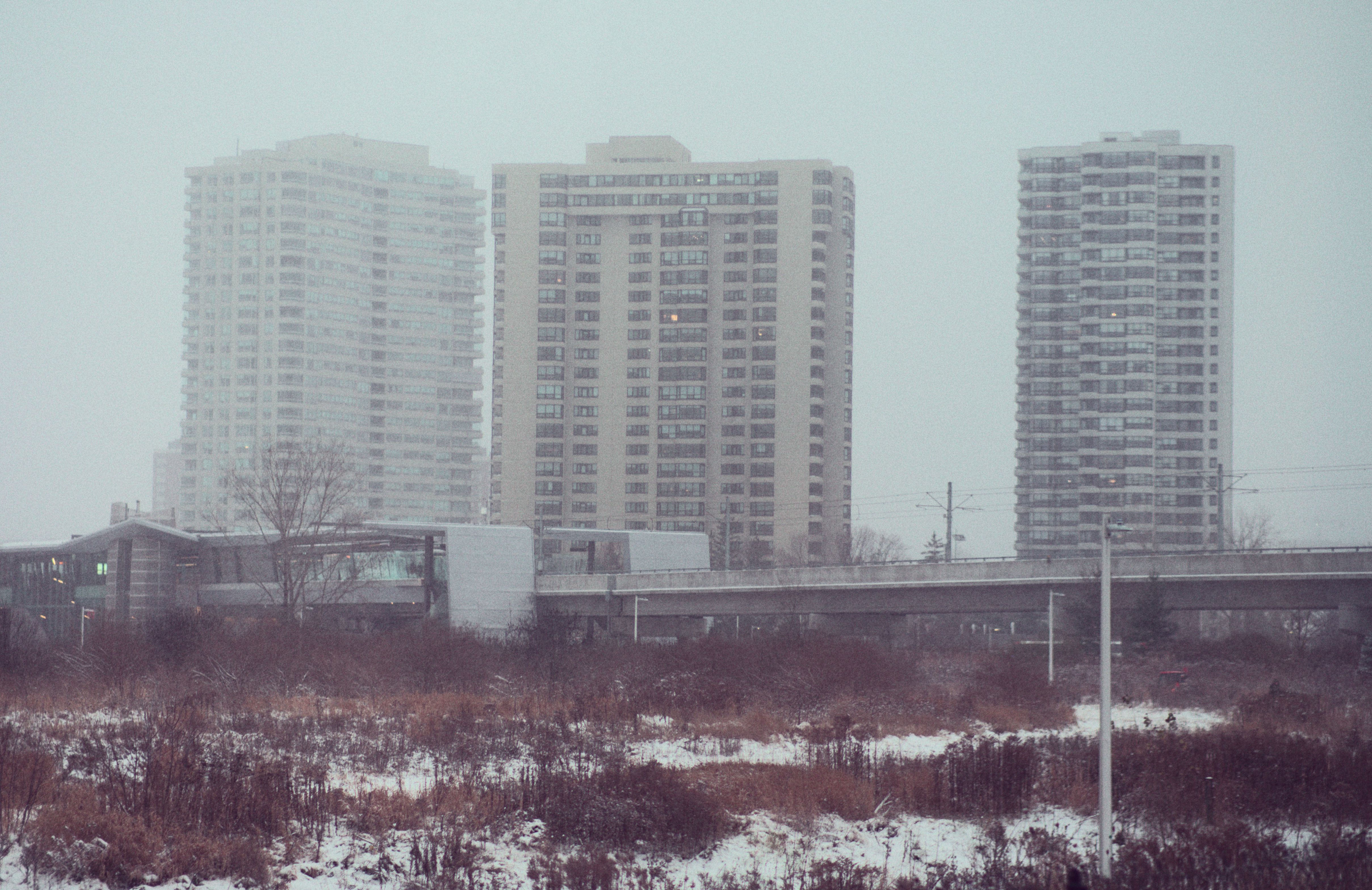 dreary looking photo of a trian station with buidlings behind it