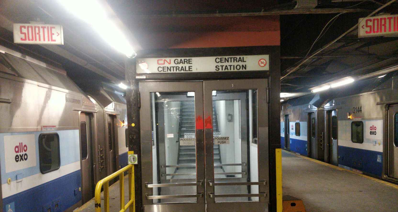 platform level at gare centrale, with two exo trains on either end with the logo allo exo. The doors to the stairs say 'CN gare centrale', with the CN logo in french, but not in english.