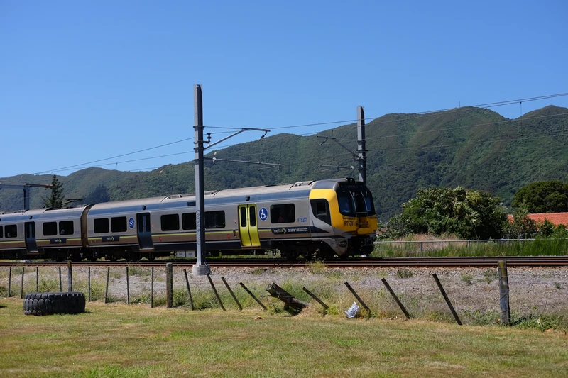 fast looking matangi train turning a bend in front of green steep hills.